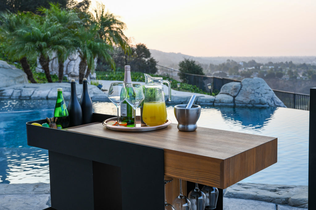 Lifestyle image of Indu+ Bar Isle by the pool, creating a perfect setting for a summer evening. The chic and versatile kitchen cart showcases refreshing drinks on the countertop, inviting you to relax and enjoy the ambiance of the outdoors.