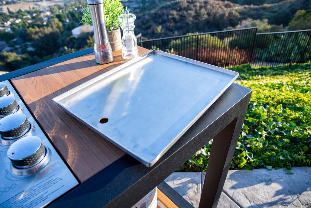 Lifestyle image of Indu+ plancha plate on the grill island, viewed from a top 45-degree angle, showcasing its versatility and functionality for outdoor cooking.