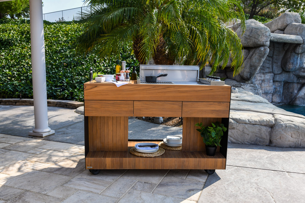 Sunny day setup of the Indu+ Bistro Island, a stylish and functional kitchen cart. With spices, plates, and a pot, it's ready for delightful outdoor grilling. Elevate your cooking experience and enjoy the sunny weather with this versatile and chic kitchen cart.