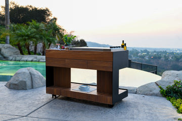Stylish lifestyle image of the Indu+ Bistro Island, a premium kitchen cart, by the pool with a beautifully lit backdrop. Elevate your outdoor cooking experience with this chic and versatile kitchen cart. Perfect for poolside gatherings, the Bistro Island combines style and functionality, adding sophistication to your outdoor space.